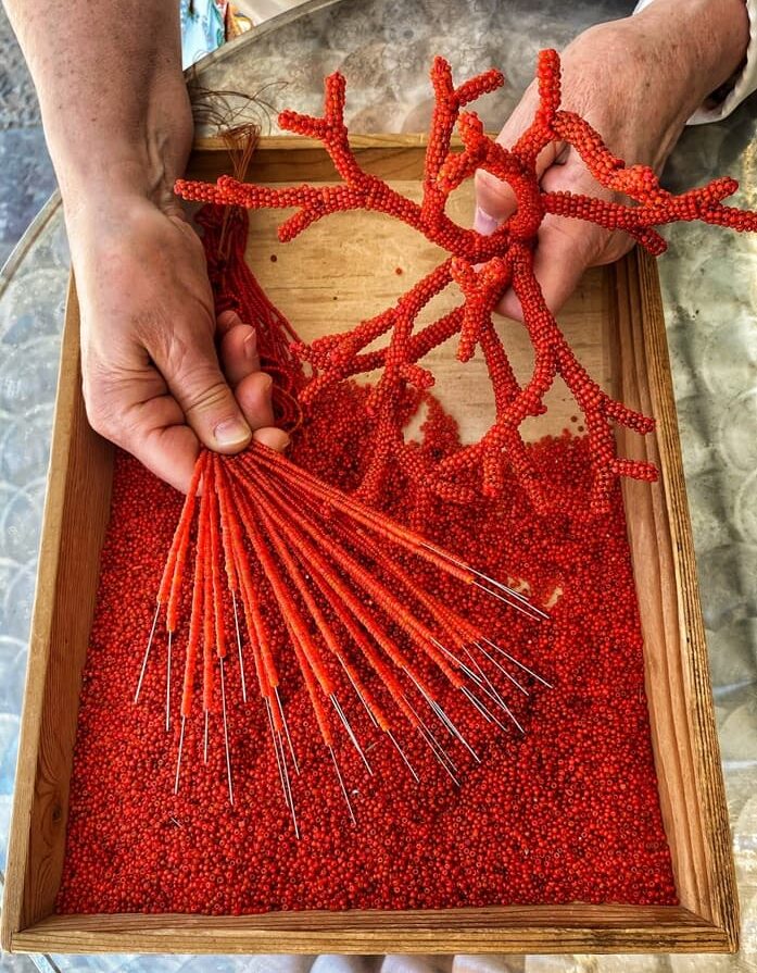An impiraressa stringing traditional Venetian glass beads